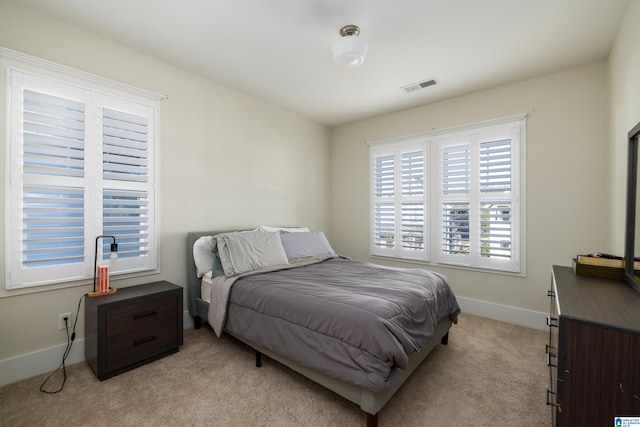 bedroom featuring visible vents, light carpet, and baseboards