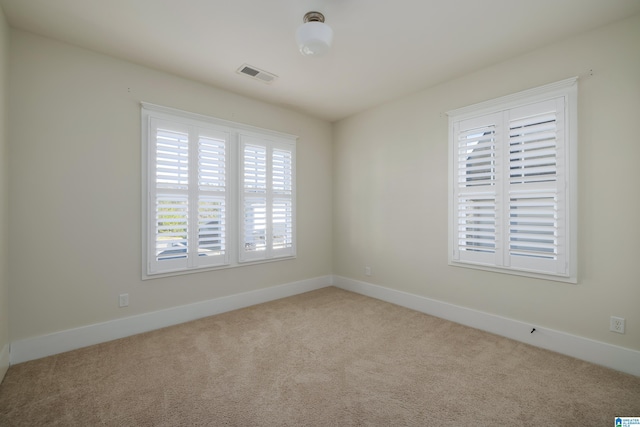 unfurnished room with carpet, visible vents, and baseboards