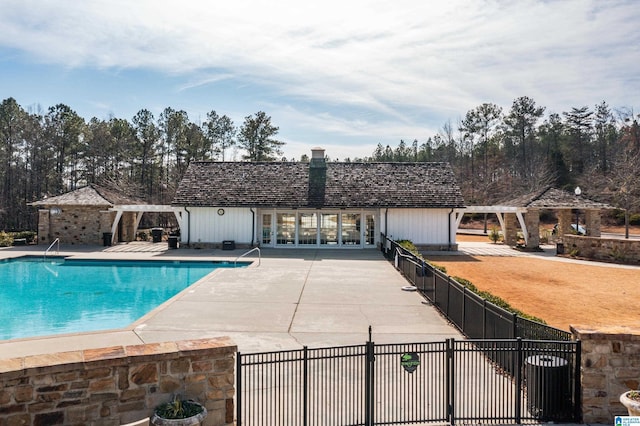 pool with french doors, a patio area, and fence