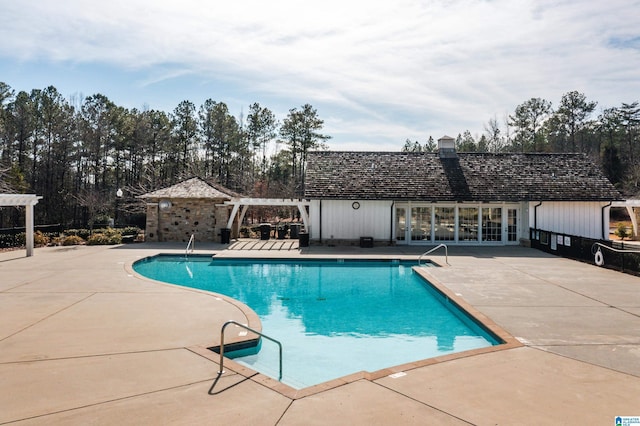 pool with an outbuilding, french doors, an exterior structure, a patio area, and a pergola