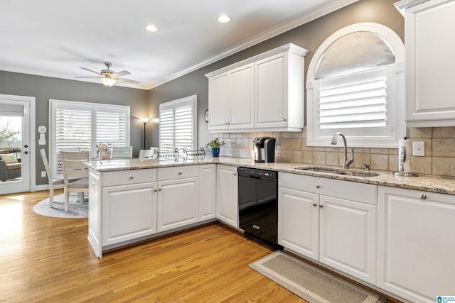 kitchen featuring a peninsula, a sink, white cabinets, black dishwasher, and crown molding