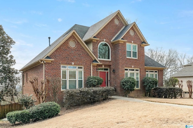 traditional-style home with brick siding, fence, and roof with shingles