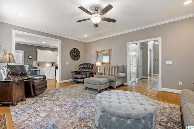 living area with a ceiling fan, light wood-type flooring, crown molding, and baseboards