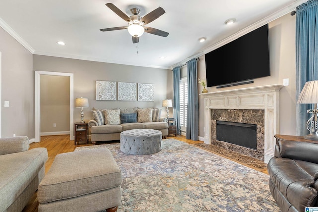 living room featuring crown molding, baseboards, ceiling fan, and wood finished floors