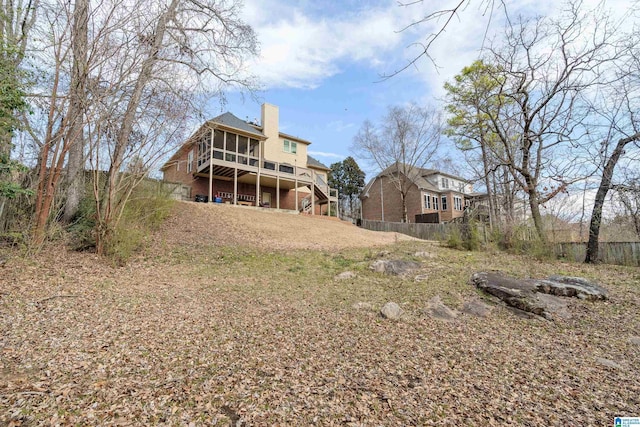 rear view of property featuring stairway, a chimney, fence, and a sunroom