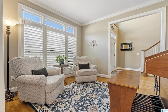 living area with crown molding, stairway, baseboards, and wood finished floors