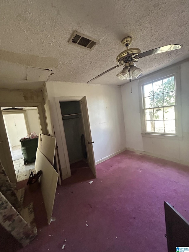 unfurnished bedroom with carpet, visible vents, ceiling fan, a textured ceiling, and baseboards