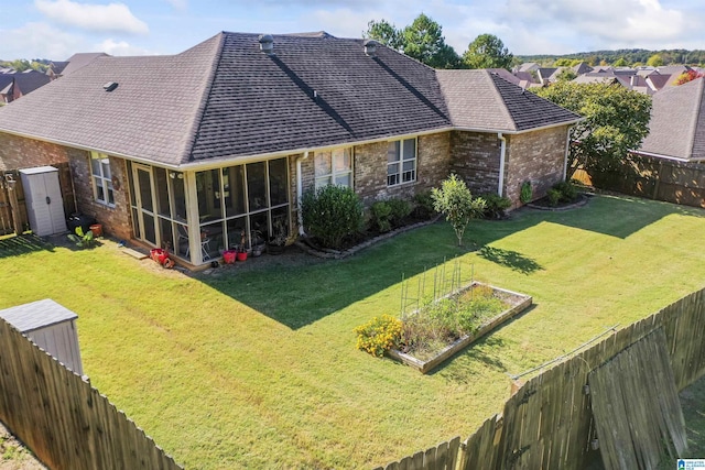 rear view of property featuring a yard, a sunroom, brick siding, and a garden