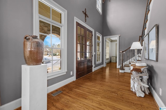 foyer featuring stairs, wood finished floors, visible vents, and baseboards