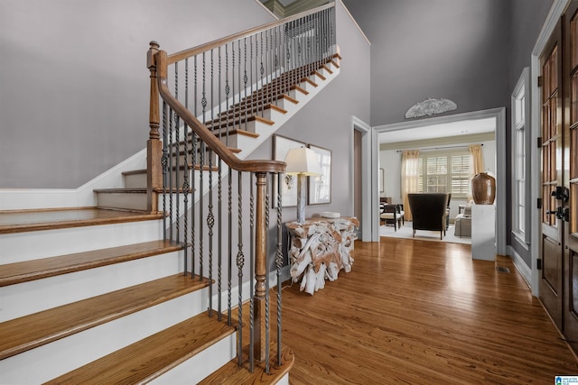 staircase featuring a towering ceiling and wood finished floors