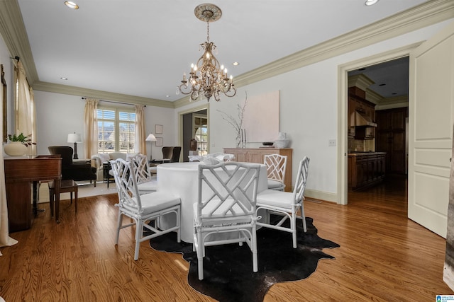 dining area with a chandelier, recessed lighting, wood finished floors, baseboards, and ornamental molding