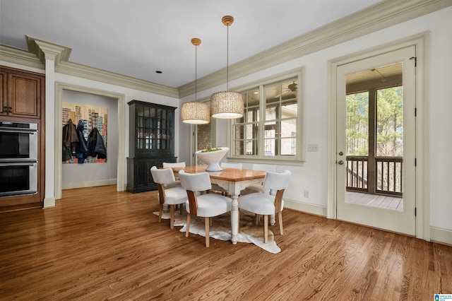 dining space with ornamental molding, light wood finished floors, and baseboards