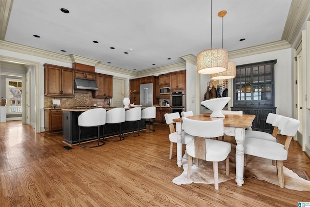 dining area featuring light wood-style floors, baseboards, and crown molding