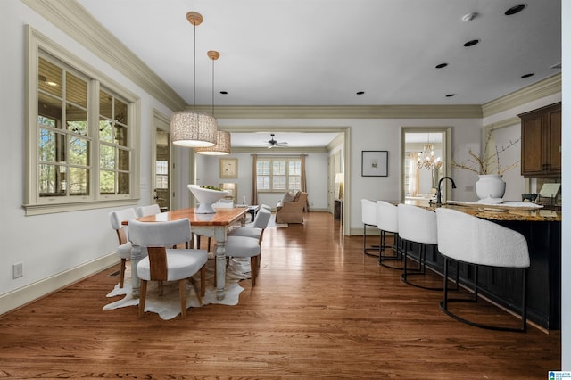 dining area featuring ornamental molding, dark wood-type flooring, a chandelier, and baseboards