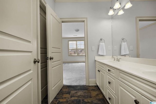 full bath with double vanity, stone finish floor, a sink, and baseboards