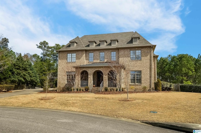 view of front facade with a shingled roof, fence, a porch, and a front lawn