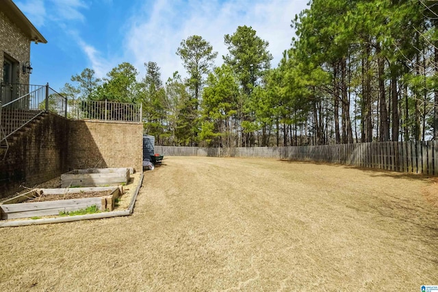 view of yard featuring stairway, fence private yard, and a garden