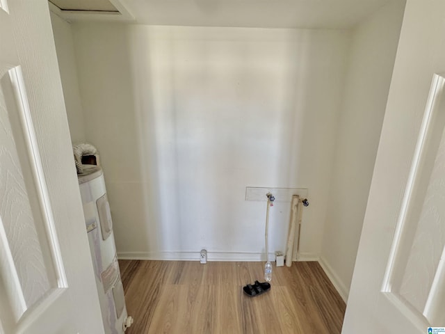 laundry area with laundry area, water heater, washer hookup, and wood finished floors