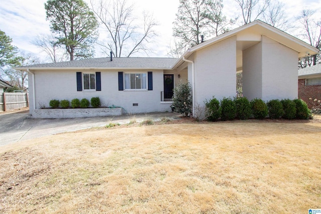 view of front of home with brick siding, crawl space, a front lawn, and fence