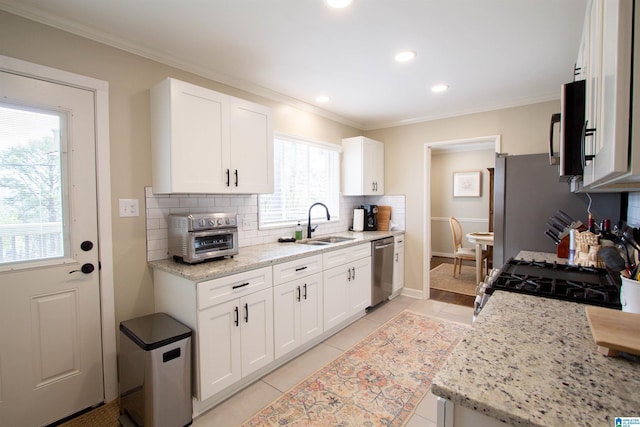 kitchen with decorative backsplash, stainless steel appliances, a sink, and ornamental molding