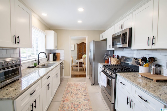 kitchen featuring crown molding, appliances with stainless steel finishes, white cabinets, and a sink