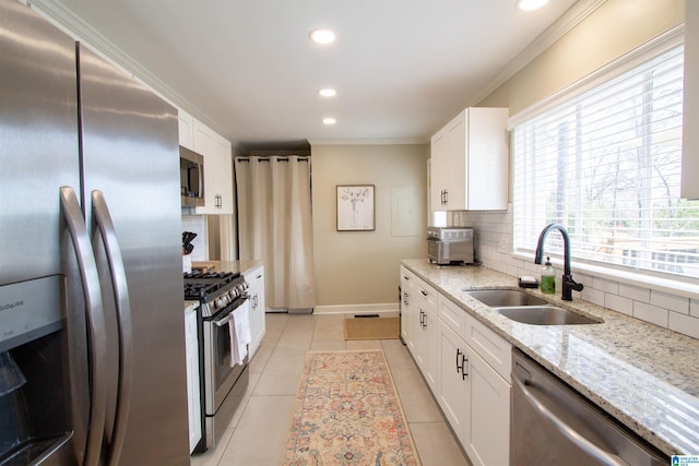 kitchen featuring appliances with stainless steel finishes, white cabinets, a sink, and ornamental molding