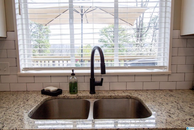 details featuring backsplash, a sink, and light stone countertops