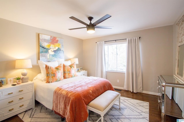 bedroom with a ceiling fan, visible vents, baseboards, and wood finished floors