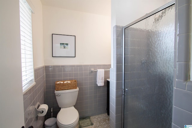 bathroom featuring tile walls, toilet, wainscoting, a shower stall, and tile patterned floors