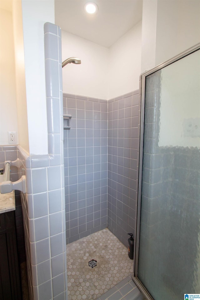 full bath with a wainscoted wall, a shower stall, and tile walls