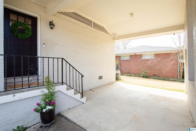 view of exterior entry with a patio, brick siding, and crawl space