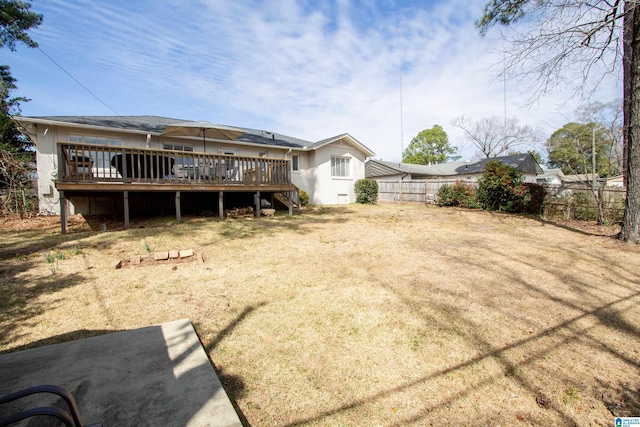 rear view of property featuring fence, a deck, and a lawn