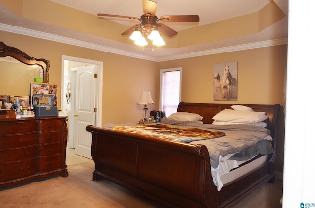 bedroom featuring light carpet, ceiling fan, a tray ceiling, and crown molding