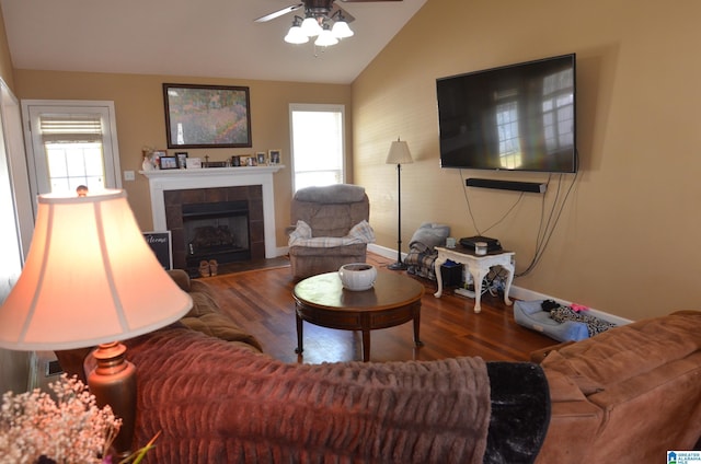 living area with a fireplace, lofted ceiling, ceiling fan, wood finished floors, and baseboards