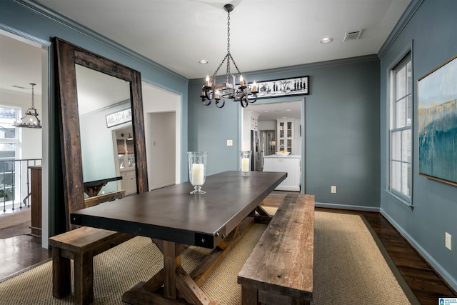 dining room with a wealth of natural light, visible vents, dark wood-type flooring, and ornamental molding