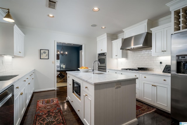 kitchen with dark wood-style floors, a center island with sink, visible vents, appliances with stainless steel finishes, and wall chimney exhaust hood