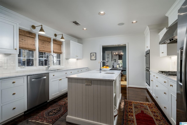 kitchen featuring a sink, crown molding, a center island with sink, and stainless steel appliances