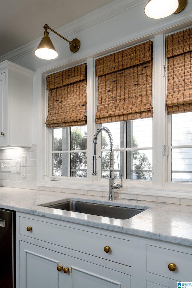 kitchen featuring white cabinets, dishwasher, crown molding, and a sink