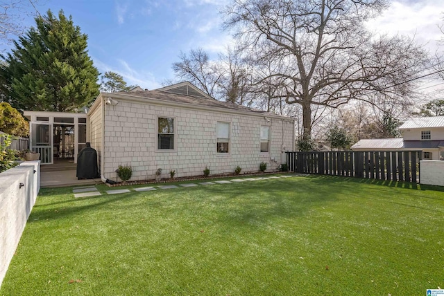 view of home's exterior with fence, a yard, and a sunroom