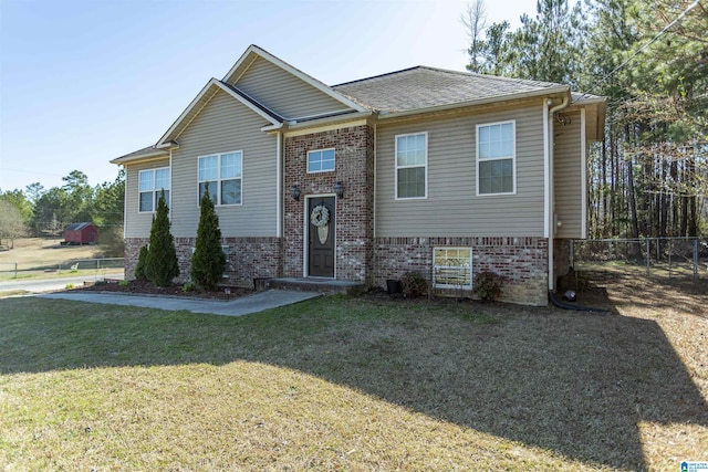 raised ranch with fence, a front lawn, and brick siding