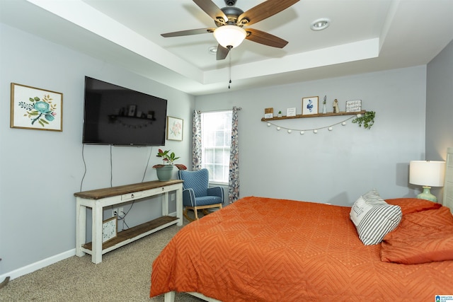 bedroom featuring carpet floors, baseboards, a tray ceiling, and a ceiling fan