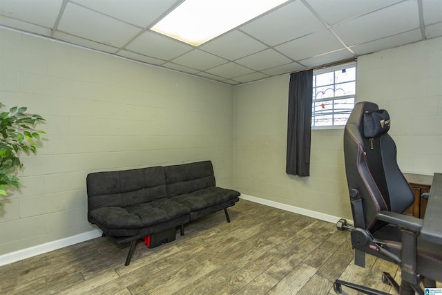 office area with a paneled ceiling, concrete block wall, and wood finished floors