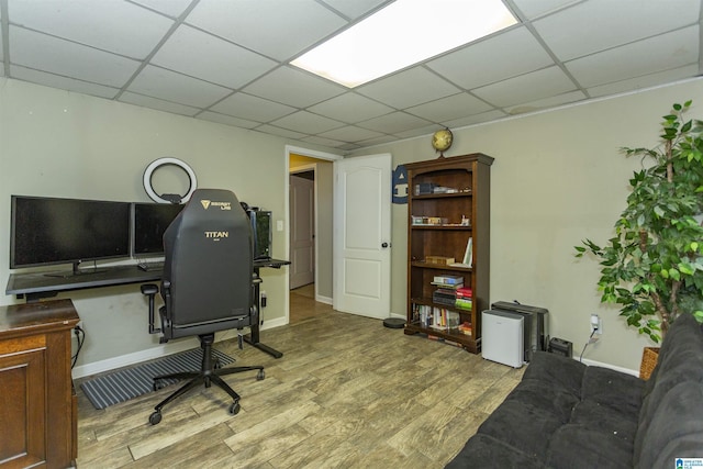 home office with baseboards, a drop ceiling, and wood finished floors