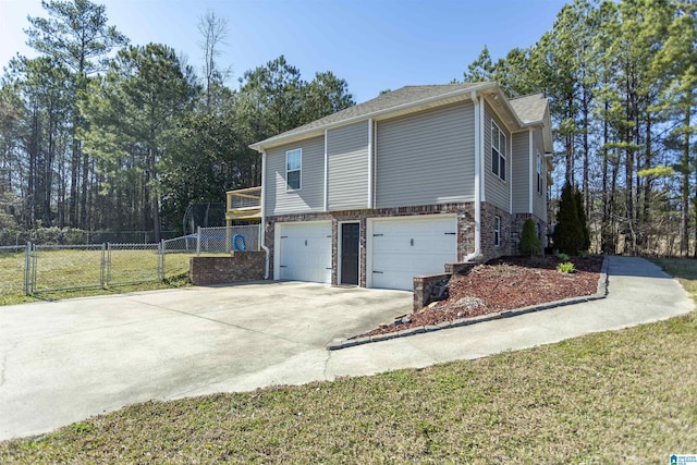 view of side of property featuring concrete driveway, an attached garage, a gate, fence, and brick siding