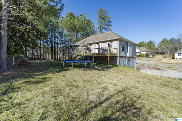 view of yard featuring a deck, a trampoline, and fence