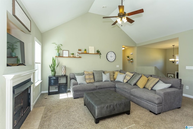 living area with baseboards, a fireplace with flush hearth, carpet floors, high vaulted ceiling, and ceiling fan with notable chandelier