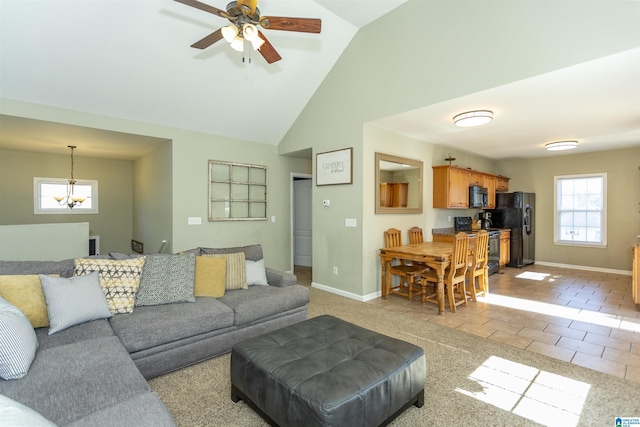 living area featuring high vaulted ceiling, ceiling fan with notable chandelier, baseboards, and light tile patterned flooring