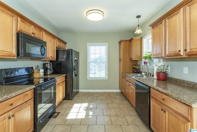 kitchen with baseboards, dark stone counters, black appliances, pendant lighting, and a sink