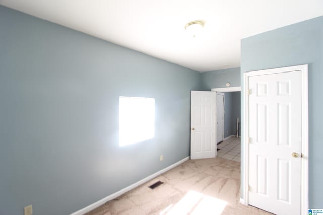 unfurnished bedroom with carpet, visible vents, and baseboards