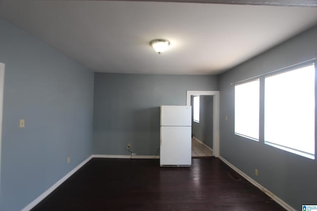 empty room featuring dark wood-type flooring and baseboards